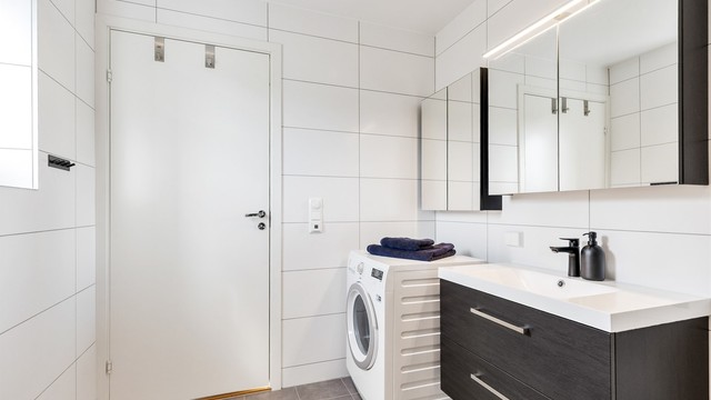 Badet er innredet med vegghengt servantinnredning med ovenpåliggende servant og armatur. Det er også høyskap og speilskap med overlys samt stikkontakt på vegg over servant.