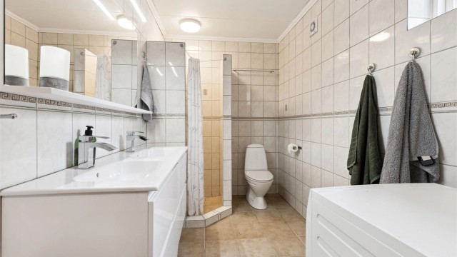 Utleiedel: Romslig, flislagt bad med dusjhjørne, dobbel servant, gulvstående toalett og plass til vaskemaskin.