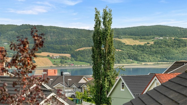 Flott utsikt i retning fjorden og det omkringliggende kulturlandskapet, med åser og grønne områder som en vakker ramme rundt nærområdet.