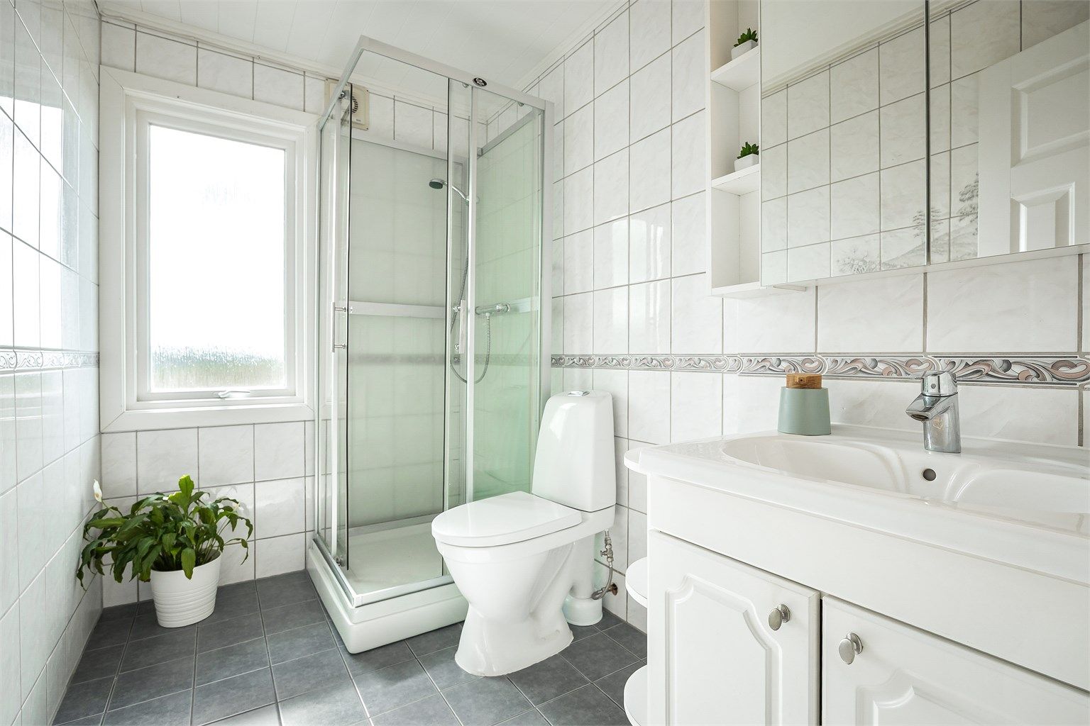Lyst bad, av eldre dato. Badet har toalett (2026), dusjkabinett og gulvvarme.
