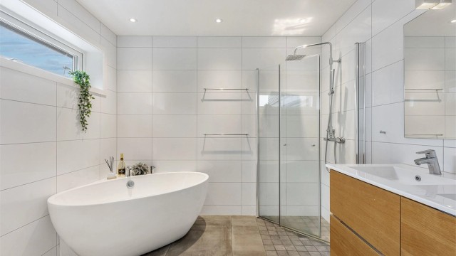 Hovedbadet i første etasje er flislagt og utstyrt med både dusjhjørne og et frittstående badekar.