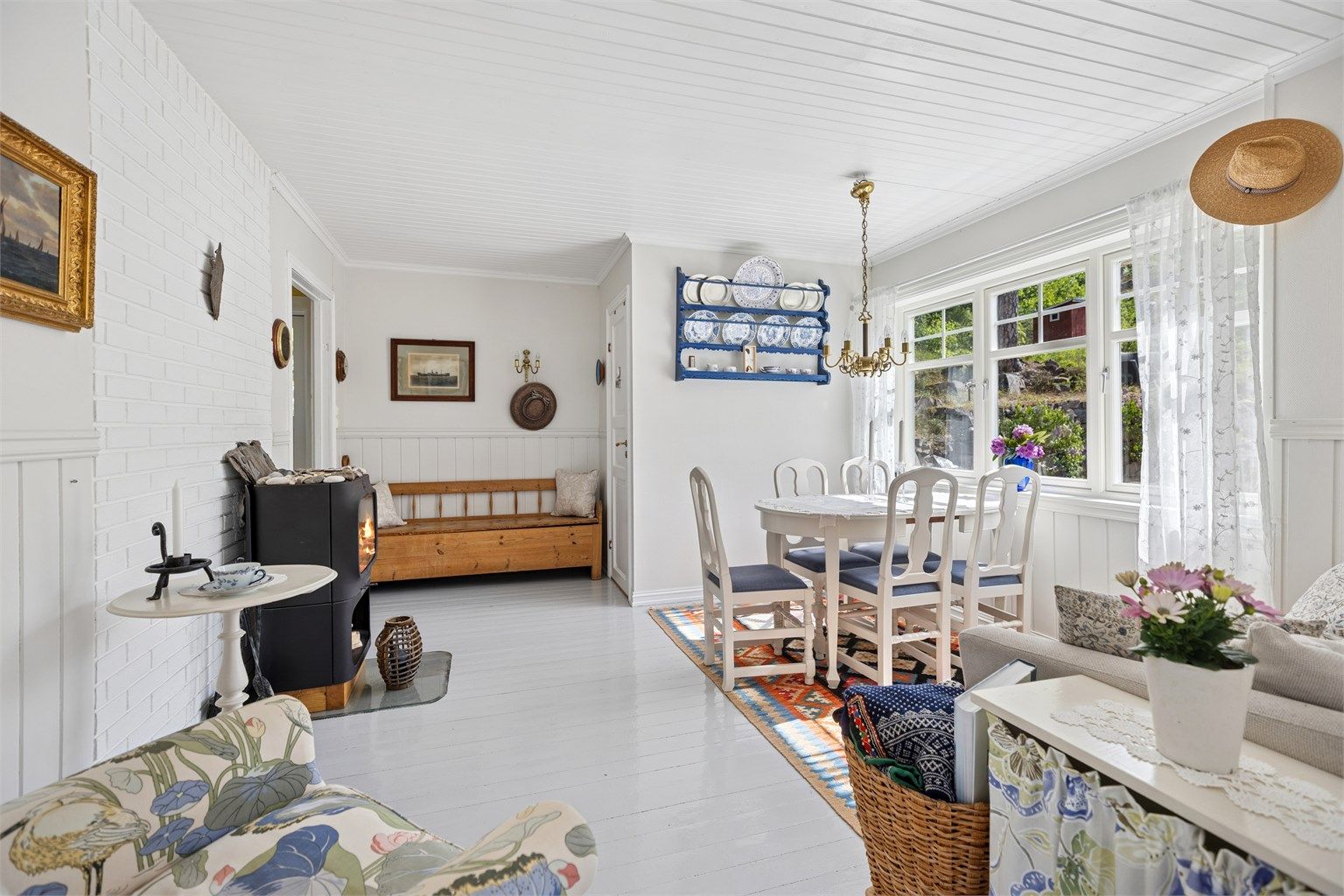 Koselig stue i klassisk hyttestil med fin peisovn og store vindusflater mot den deilige hagen og utsikten