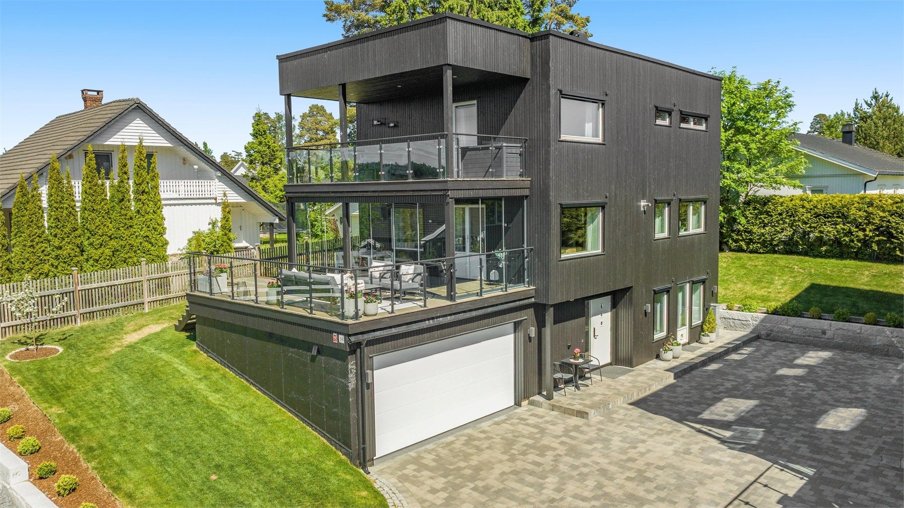 Fasaden har stående bordkledning og et moderne uttrykk med store vindusflater.