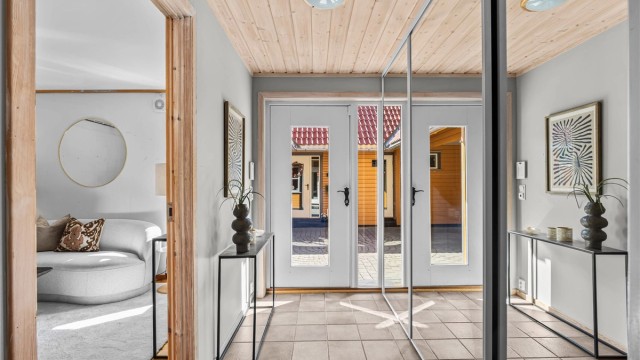 Romslig entré med stor skyvedørsgarderobe for oppbevaring av yttertøy.