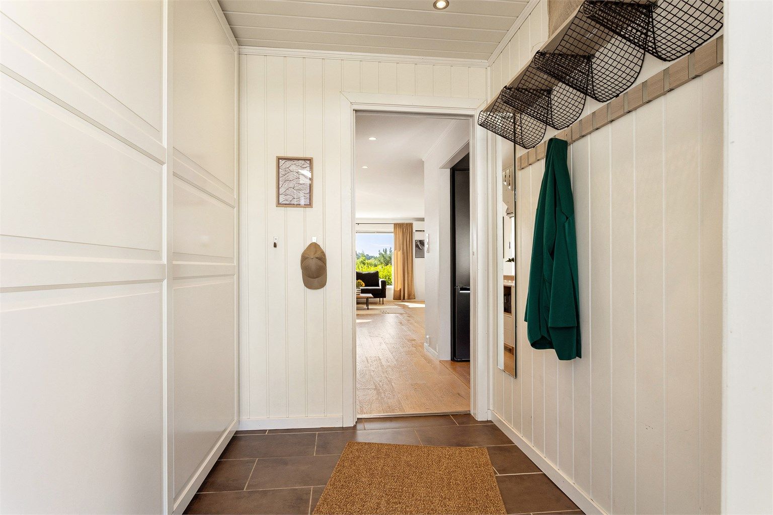 Praktisk entré med flislagt gulv, behagelig gulvvarme og skyvedør med glassfelt som slipper lyset videre inn i boligen.