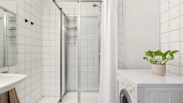 Badet er utstyrt med dusjkabinetg samt servant med overskap med speildører.