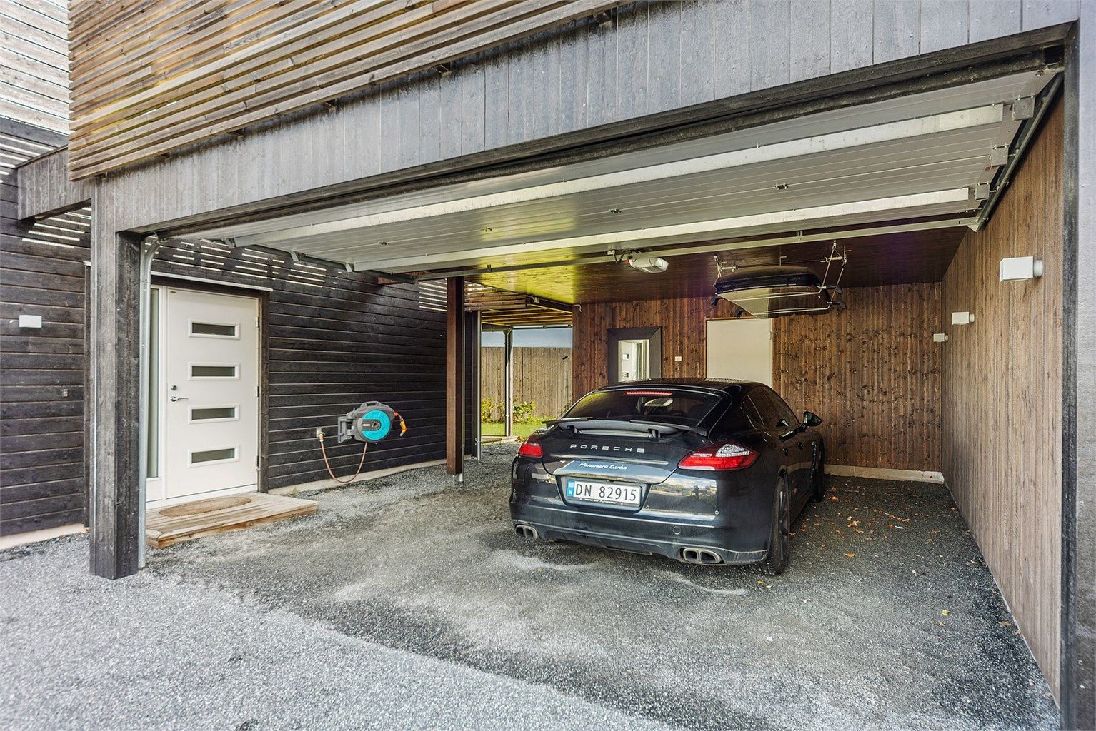 Boligen har en dobbel garasje/carport-løsning med sportsbod i bakkant.