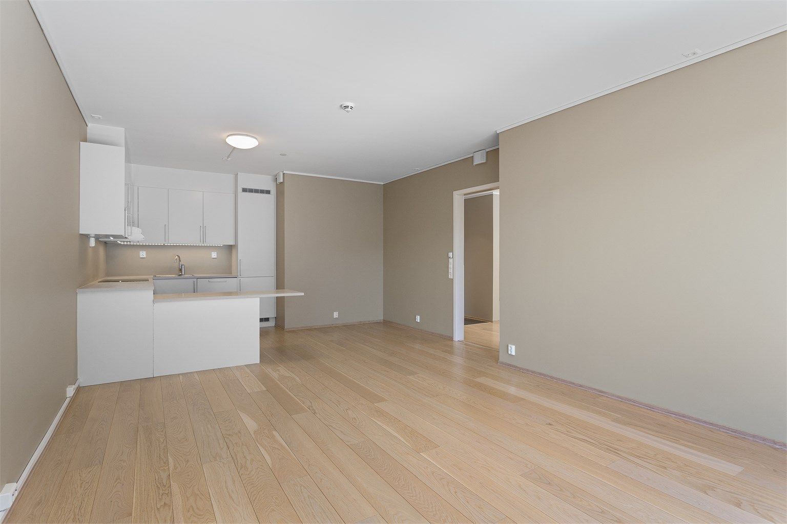 Den åpne planløsningen mellom stue og kjøkken skaper en sosial og luftig atmosfære.