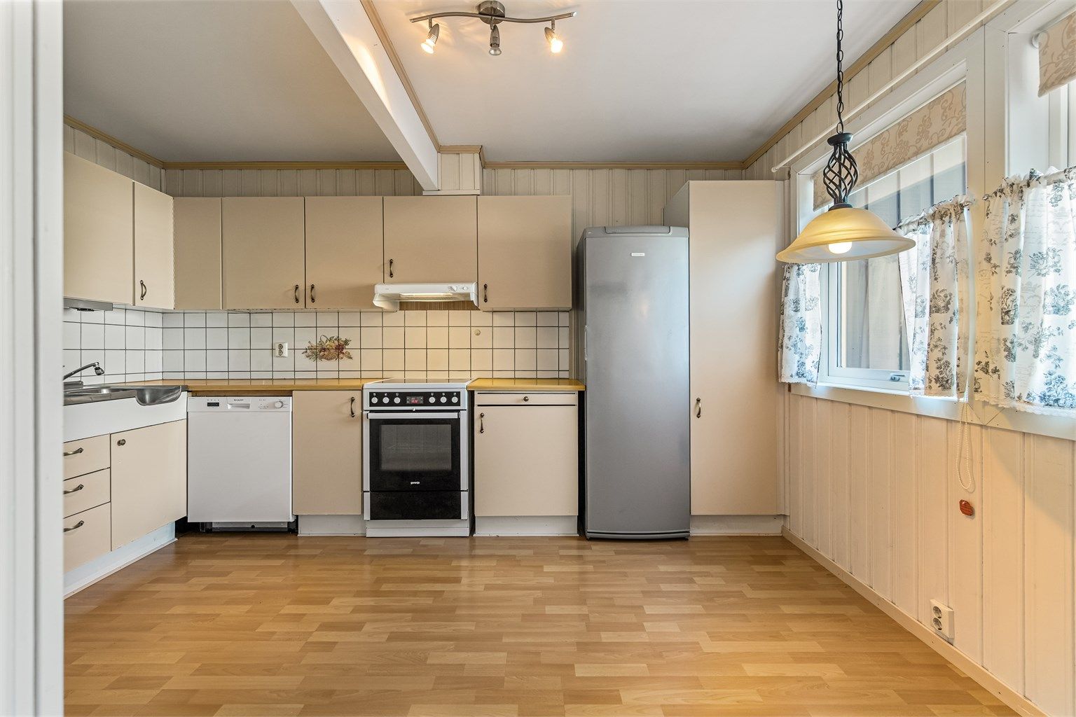 Kjøkken med glatte fronter, laminatbenkeplate og god plass til spisebord ved vinduet.