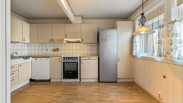 Kjøkken med glatte fronter, laminatbenkeplate og god plass til spisebord ved vinduet.