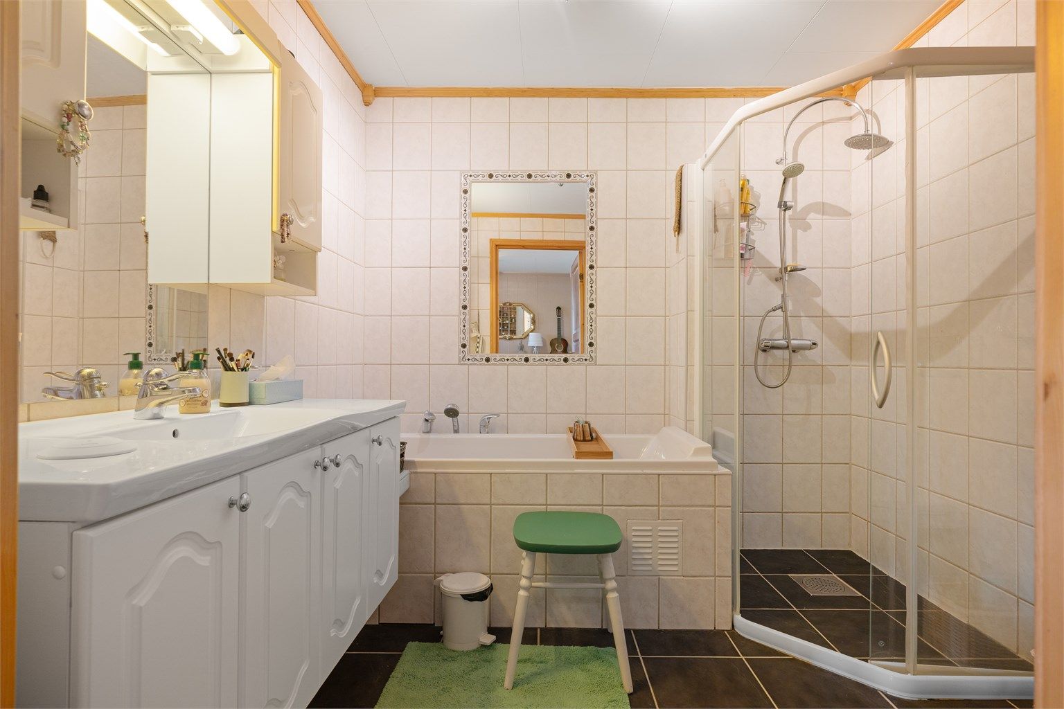 Pent flislagt bad på 6 kvm med gulvvarme og servantskap med overskap og speil med lys, vegghengt toalett, dusjhjørne med regndusj samt badekar.