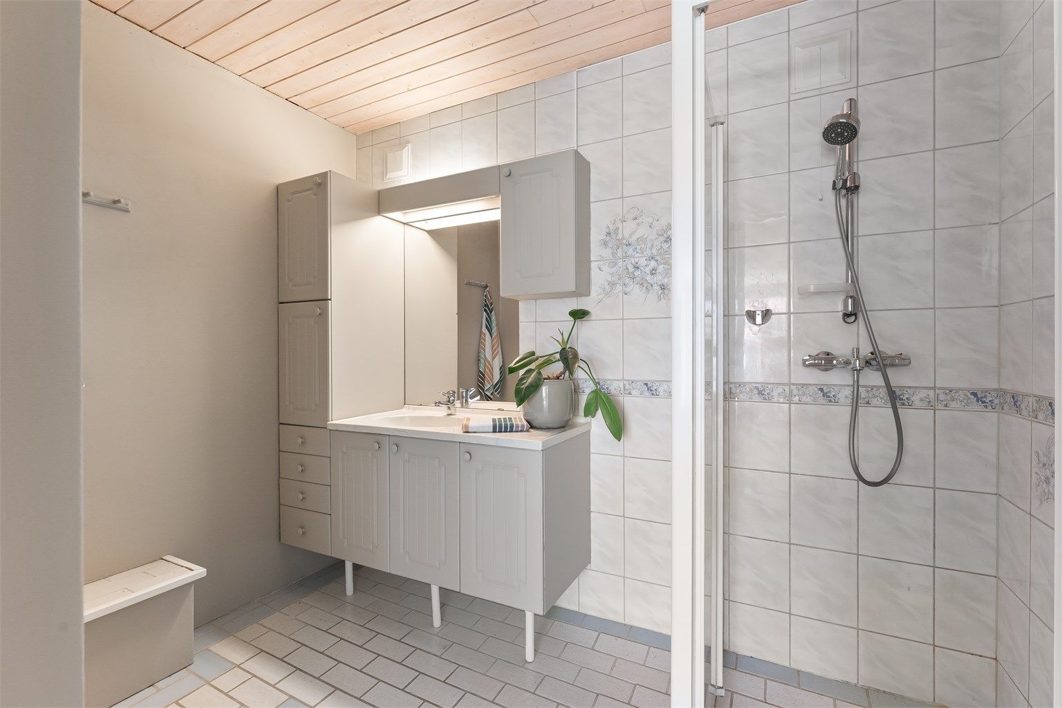 Badet i underetasjen er fra byggeåret, med flislagt gulv med gulvvarme og dusj på gulv med glassdør.