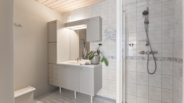 Badet i underetasjen er fra byggeåret, med flislagt gulv med gulvvarme og dusj på gulv med glassdør.