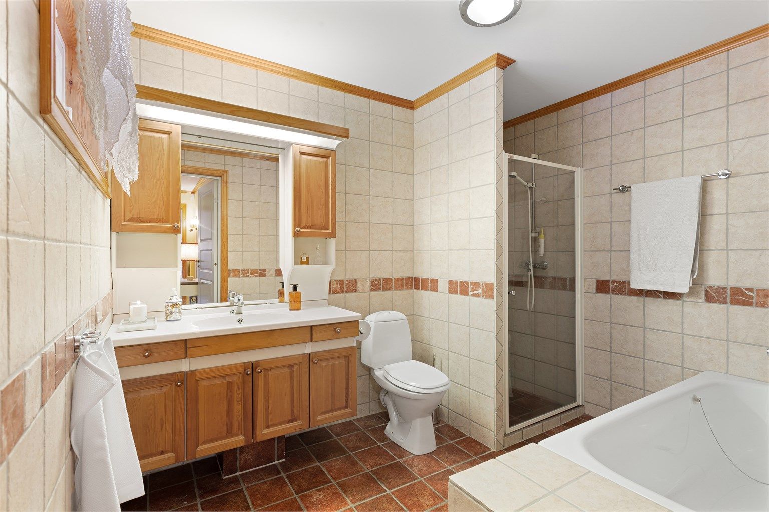 Stort flislagt bad med badekar og dusjnisje.