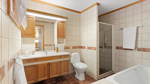 Stort flislagt bad med badekar og dusjnisje.