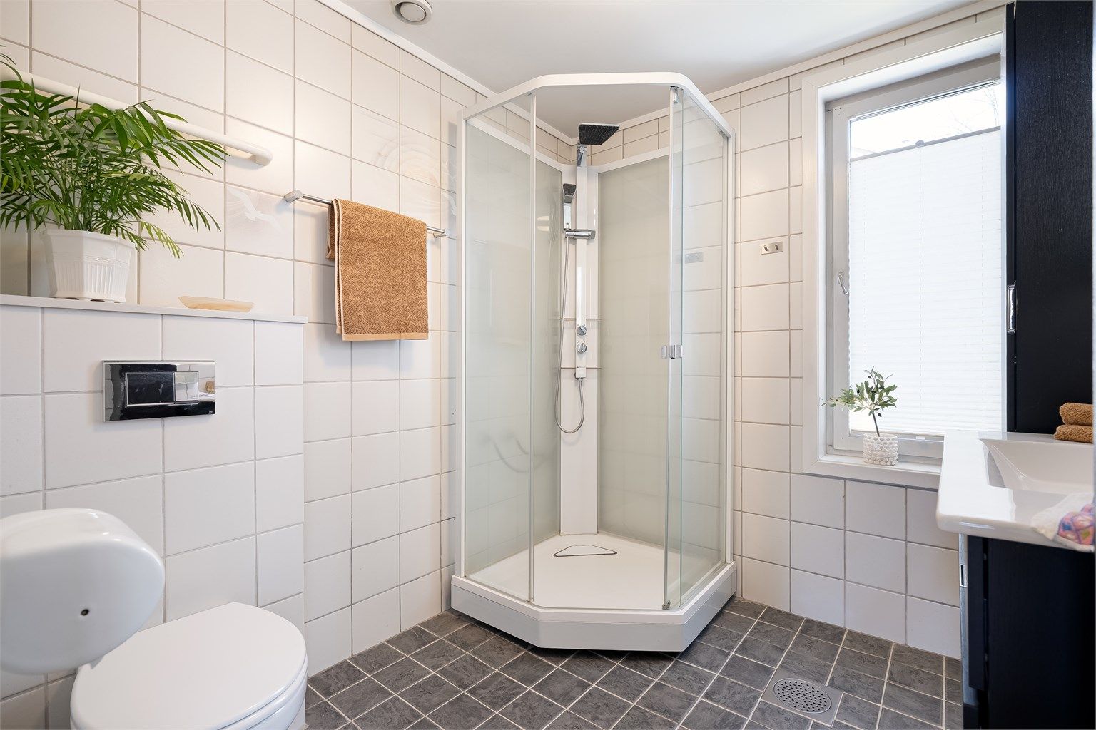 Badet er innredet med vegghengt servantinnredning og ovenpåliggende servant med armatur, samt speil med sidelys.