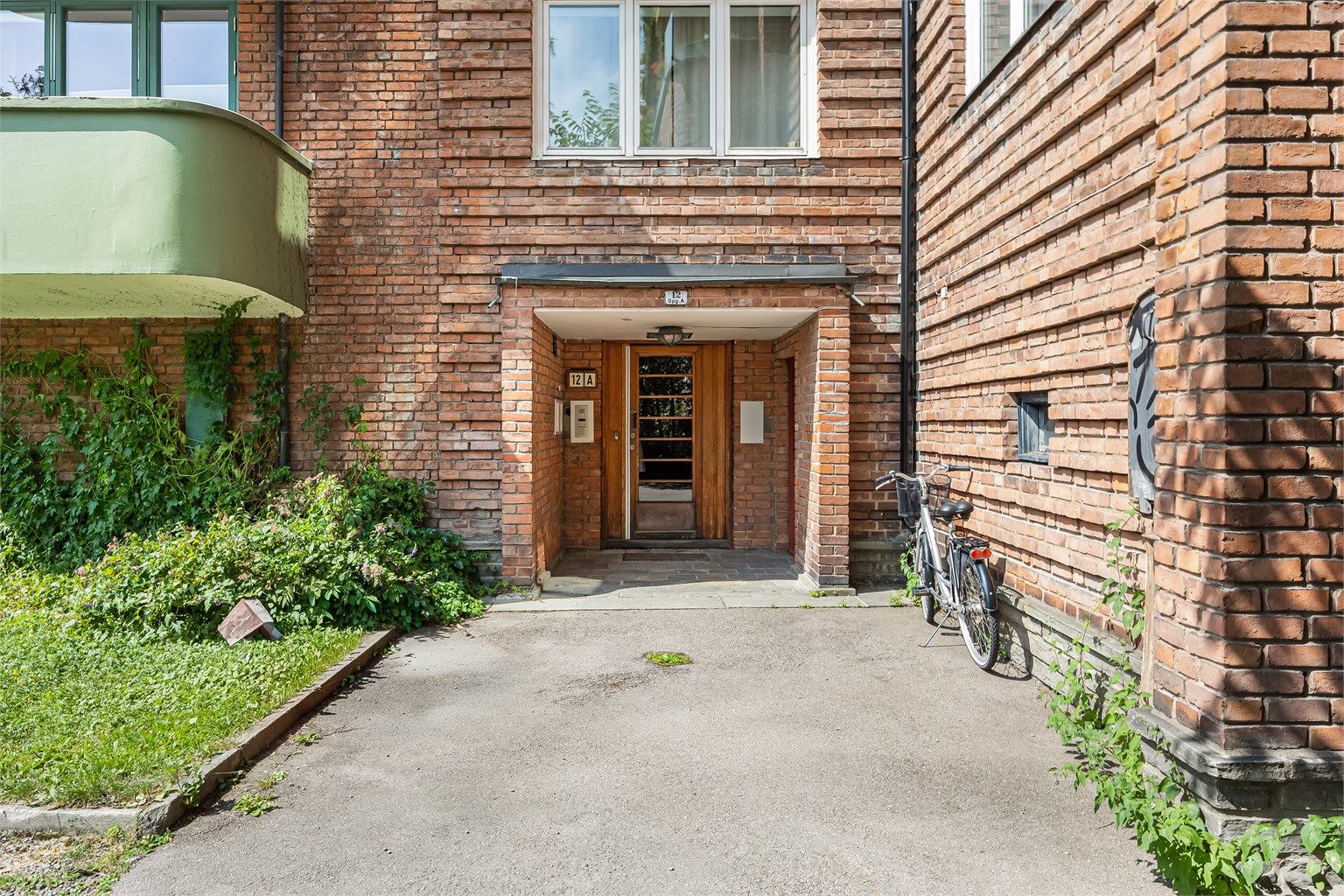 Karakteristisk bygård fra 1931 med teglsteinsfasade. Inngang til felles trapperom. 