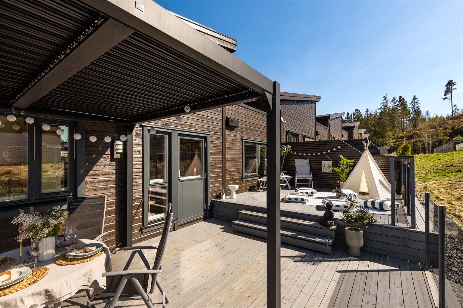 Pergolaen skaper en lun og definert sone for spiseplassen utendørs.