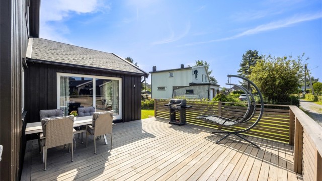 Den store terrassen har god plass til flere sittegrupper og trapp ned til hagen.