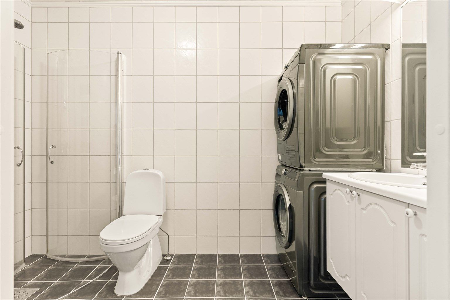 Badet i hovedetasjen har flislagt gulv med gulvvarme og praktisk opplegg for vaskesøyle.