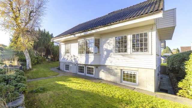 Boligen ligger fint til i terrenget med oppmurt natursteinsmur mot hovedveien.