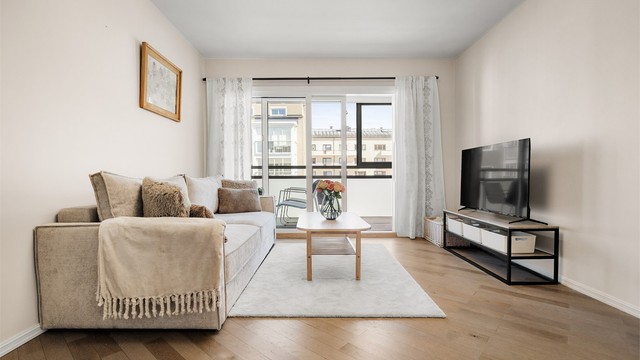 Lys stue med plass til sofagruppe og tv-møblement.
