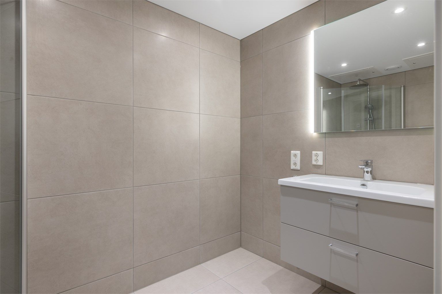 Lekkert og flislagt bad med vannbåren gulvvarme. Badet har store fliser på vegger og gulv i moderne farger, noe som gir "spa-følelse"