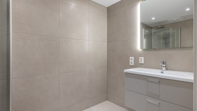 Lekkert og flislagt bad med vannbåren gulvvarme. Badet har store fliser på vegger og gulv i moderne farger, noe som gir "spa-følelse"