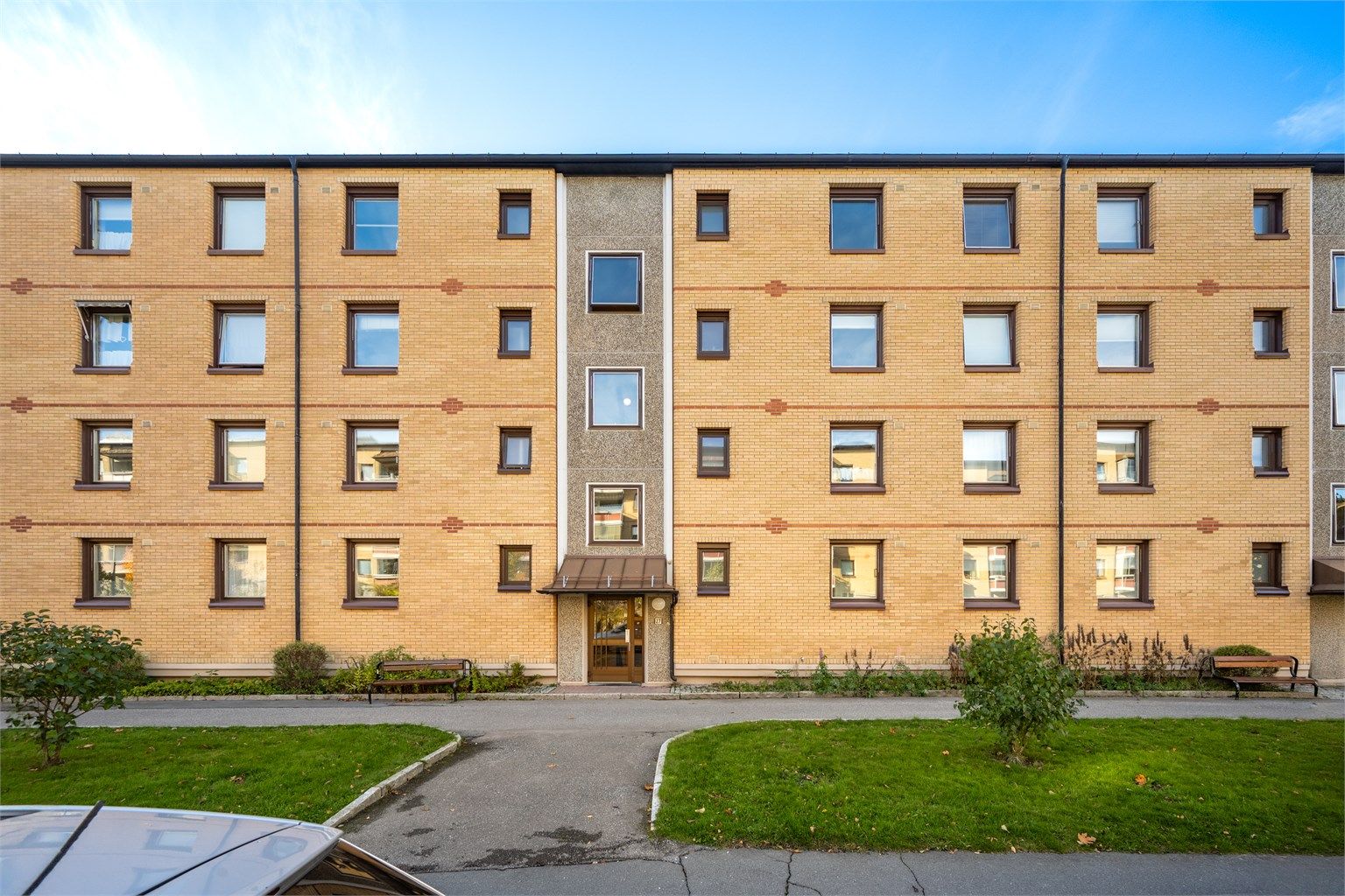 Inngangsparti med asfaltert adkomst og benker.