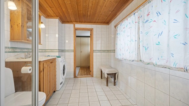 Flislagt bad med gulvvarme, dusjhjørne, servant, gulvstående toalett og opplegg for vaskemaskin