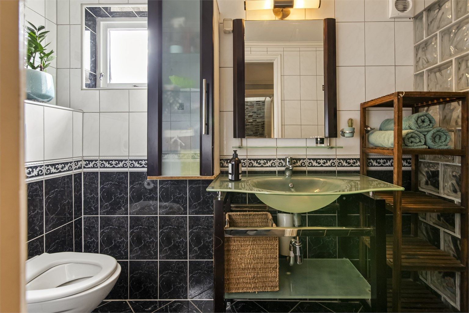 Badet i underetasjen har flislagt gulv med gulvvarme og en dusjnisje med vegg i glassbyggerstein.