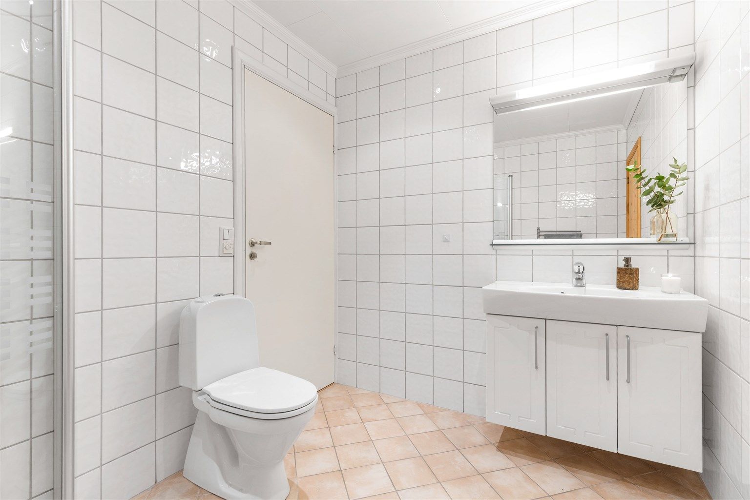 Baderom med flislagt gulv med varme og flislagte vegger. Nedsenket himling med downlights. Vegghengt servantskap. Ovenpåliggende servant med ett-greps armatur.