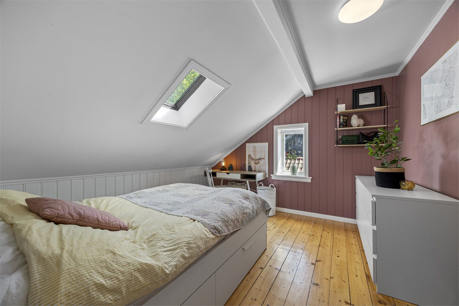 Soverom med plass til seng og arbeidsplass under takvinduet.