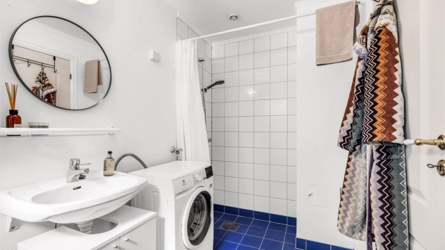 Lyst baderom fra byggeår med flislagt gulv og gulvvarme.