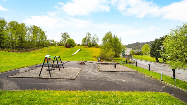 Store, grønne fellesområder med lekeapparater og ballbinge nedenfor borettslaget