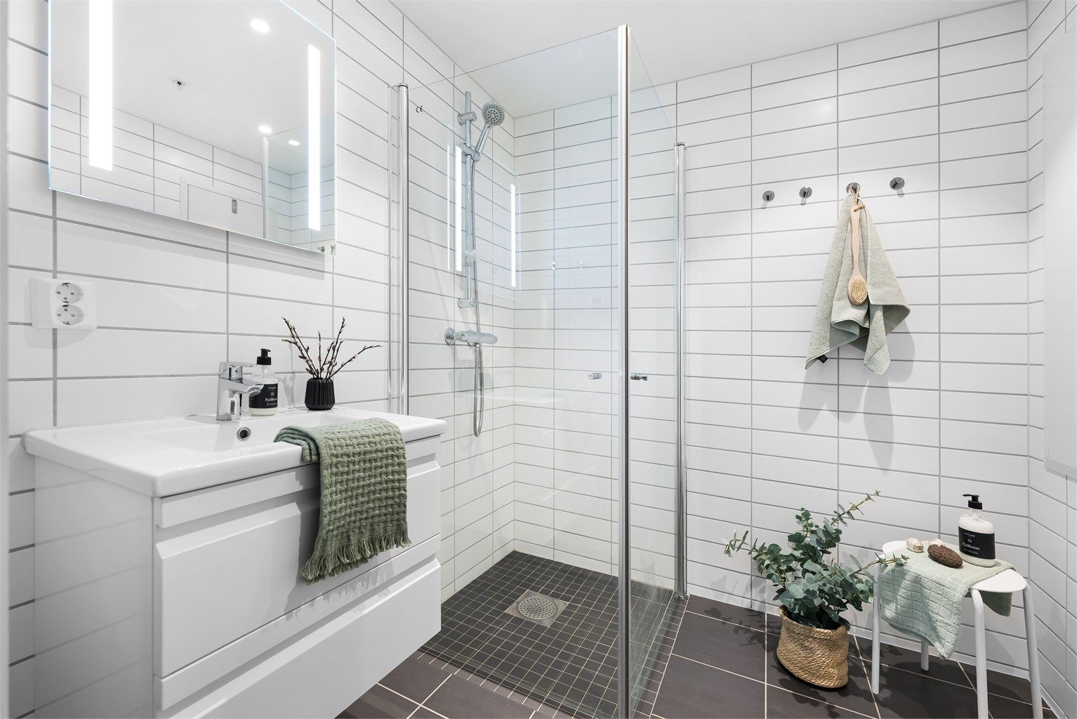 Helfliset bad fra byggeår som er innredet med baderomsmøbler, praktisk dusjhjørne med innfellbare dører og vegghengt wc.