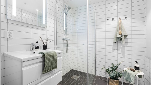 Helfliset bad fra byggeår som er innredet med baderomsmøbler, praktisk dusjhjørne med innfellbare dører og vegghengt wc.