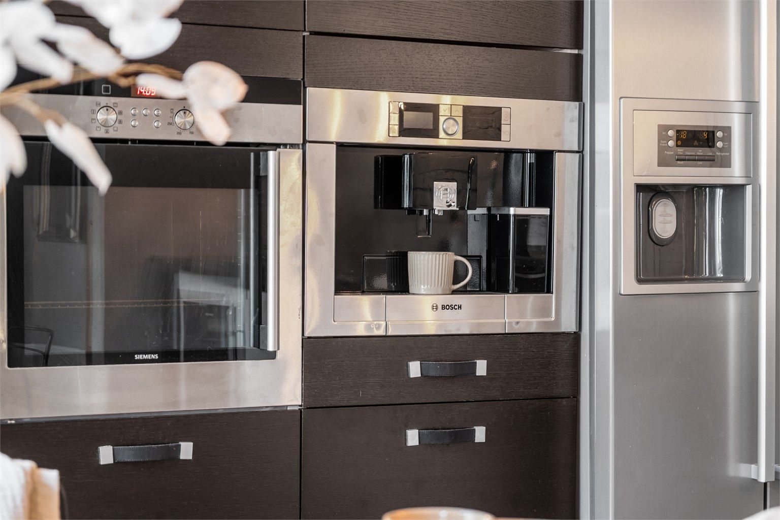 Benkeskapsbelysning og stikkontakter over kjøkkenbenk. Integrert stekeovn, platetopp, oppvaskmaskin, kaffemaskin og kjøleskap med fryser.