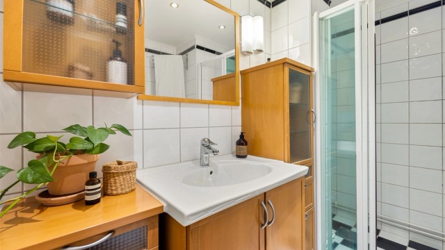 Badet er innredet med servantskap, ovenpåliggende servant, speil og dusjsone med skyvedør i glass. Baderommet er fra 2000 og renovert i regi av aksjelaget.