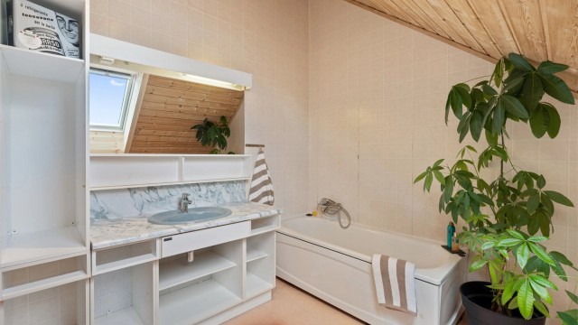 Badet er innredet med badekar og servantinnredning med god lagringsplass.
