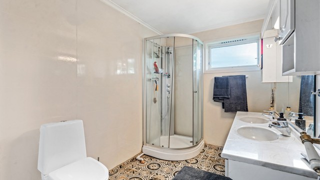 Badet i hovedetasjen er utstyrt med toalett og dusjkabinett.