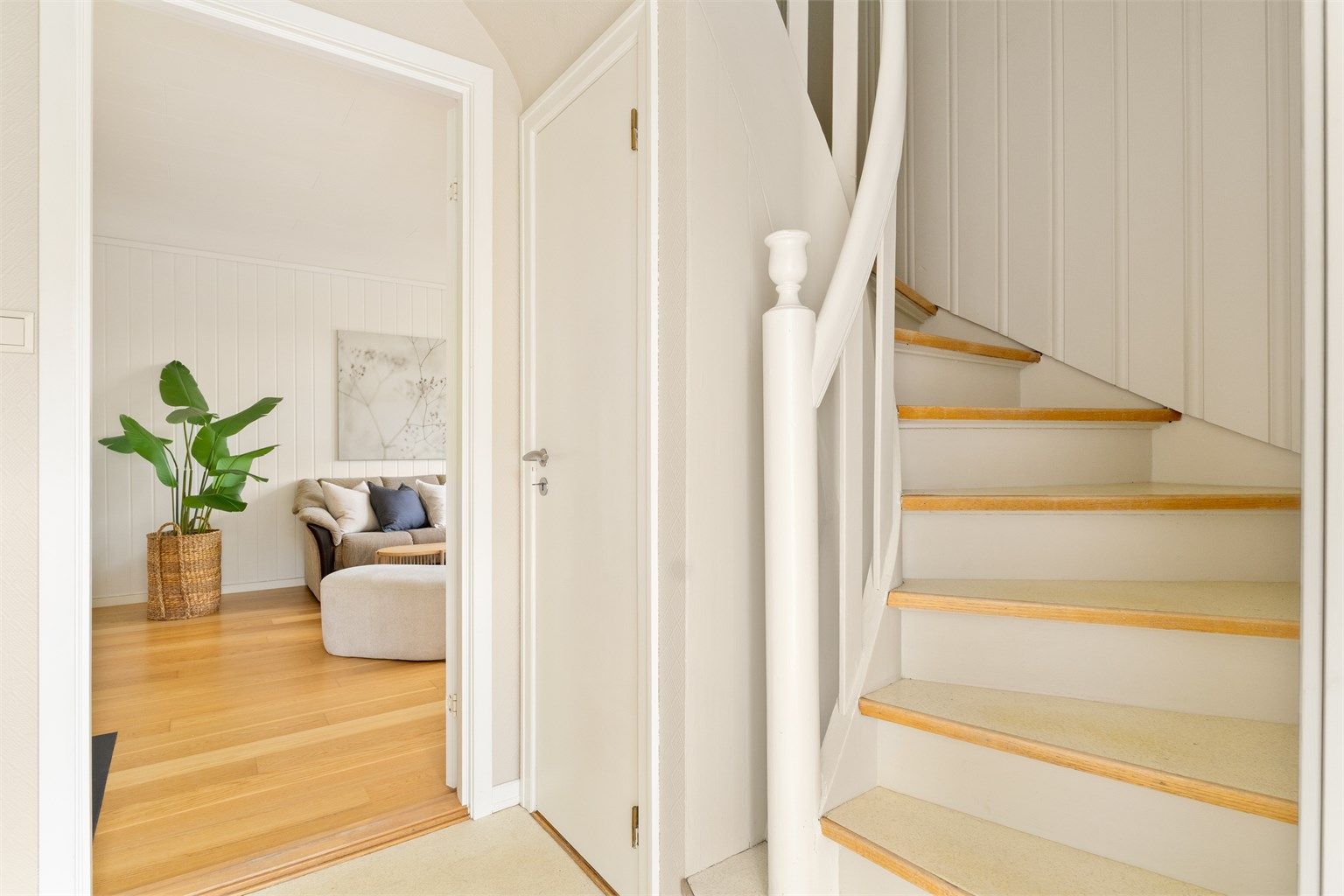 Entréen i 1. etasje leder inn til bad og stue. Trappen fører opp til boligens loftsetasje.