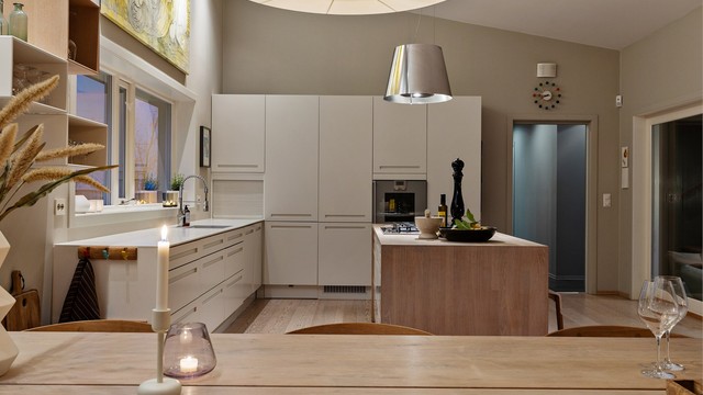 Åpen kjøkkenløsning mot stue. Kjøkkeninnredning med slette fronter. Benkeplate av tre og laminat. Nedfelt oppvaskkum med ett-greps armatur. Stikkontakter på vegg over kjøkkenbenk.