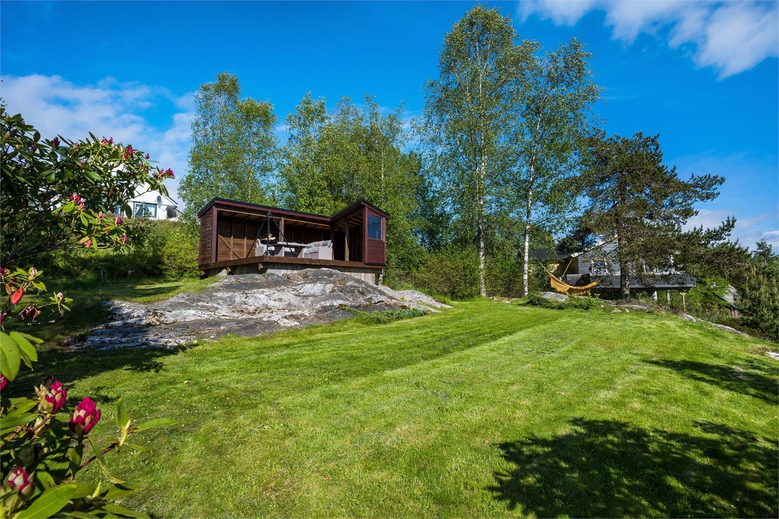 Øvre del av tomten er opparbeidet med plenareal og fin solplass.