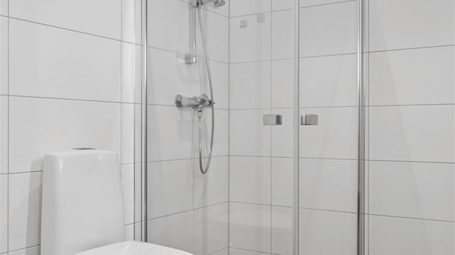 Rommet er utstyrt med vegghengt servantinnredning, dusjhjørne og toalett.