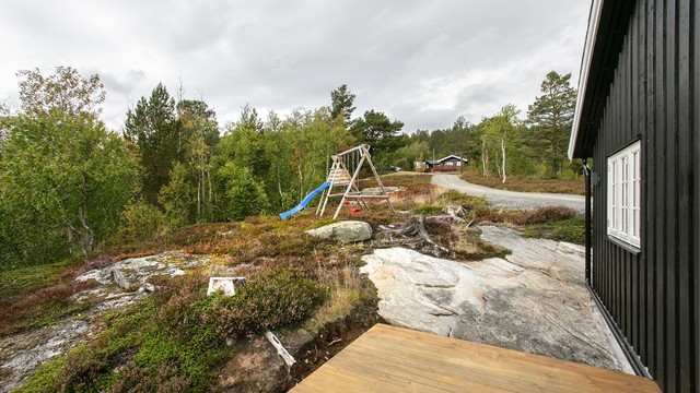 Tomten er opparbeidet med naturlig fjellbunn, lyng og lekeplass.