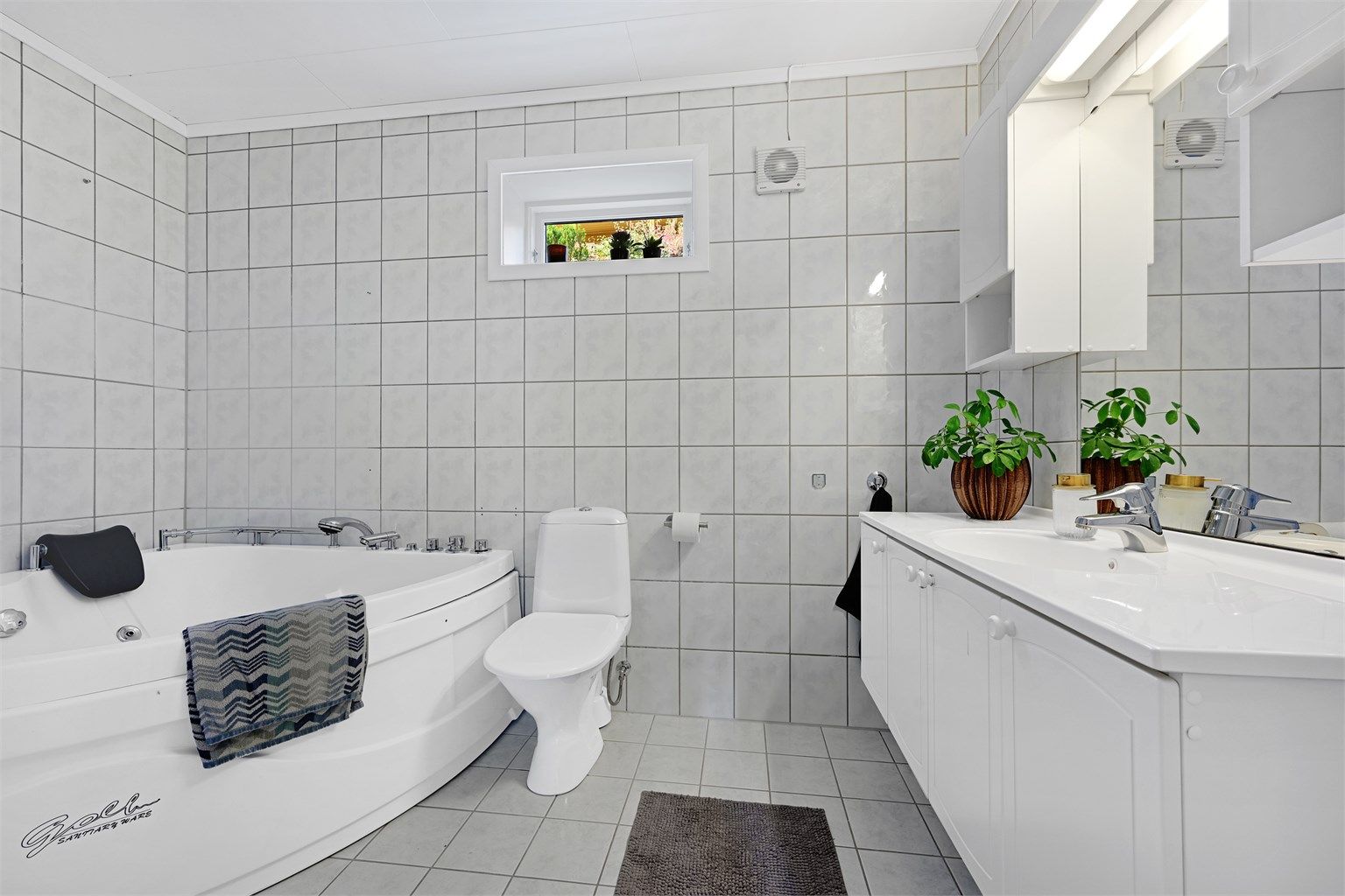 Badet er innredet med servantskap, toalett og badekar.