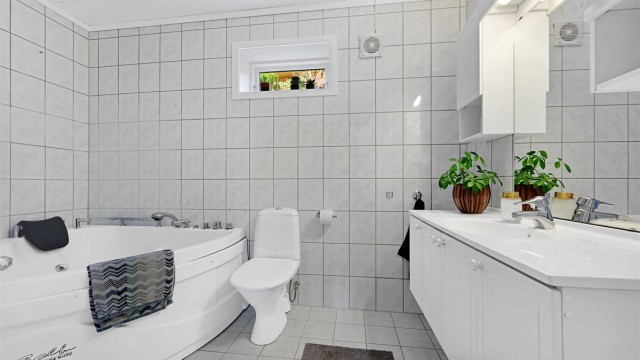 Badet er innredet med servantskap, toalett og badekar.