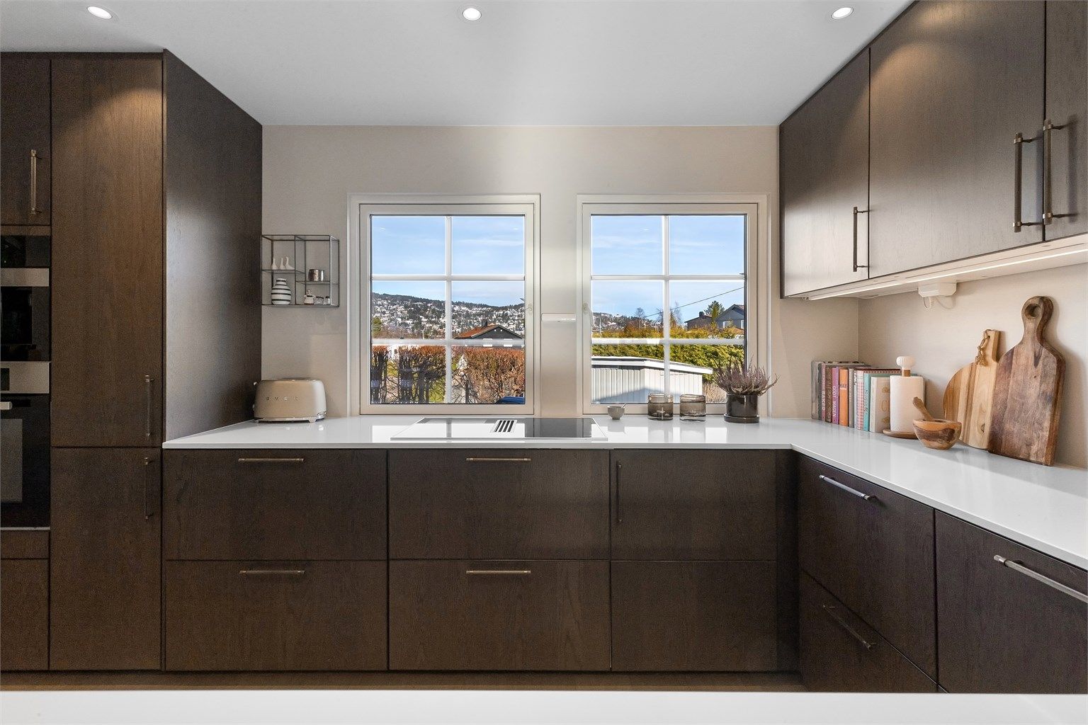 Stilrent kjøkken med slette fronter på skap og skuffer, og benkeplate i komposittsten