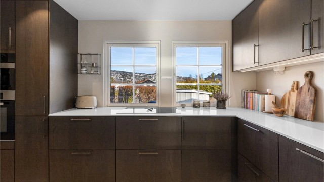 Stilrent kjøkken med slette fronter på skap og skuffer, og benkeplate i komposittsten